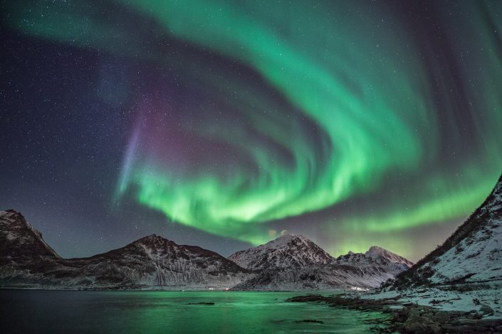 Nordlicht über verschneiten Bergen der Lofoten