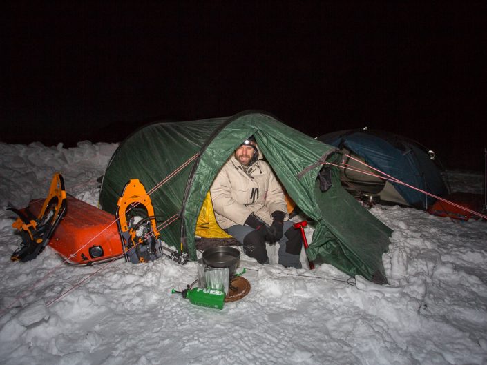 Mann im Zelt, im Winter beim Schneeschmelzen, Dovrefjell Nationalpark, Norwegen